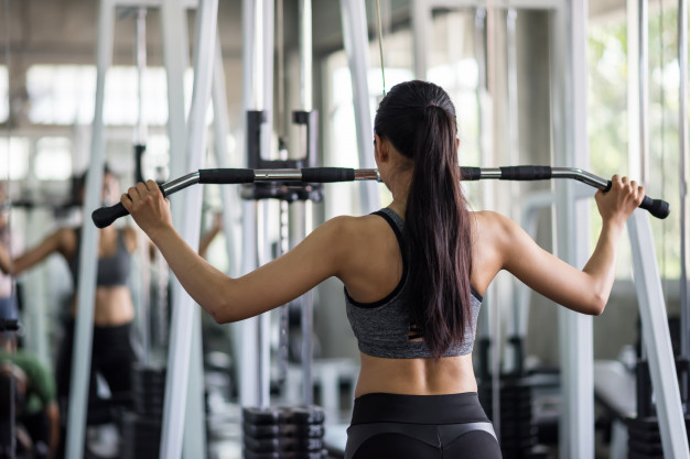 Premium Photo | Woman pump back muscles exercise in gym